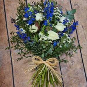 Seasonal blue and white sheaf funeral flowers arranged with fresh blooms