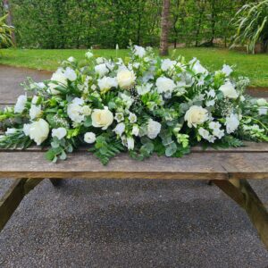 White funeral flowers double-ended coffin spray with roses and seasonal blooms